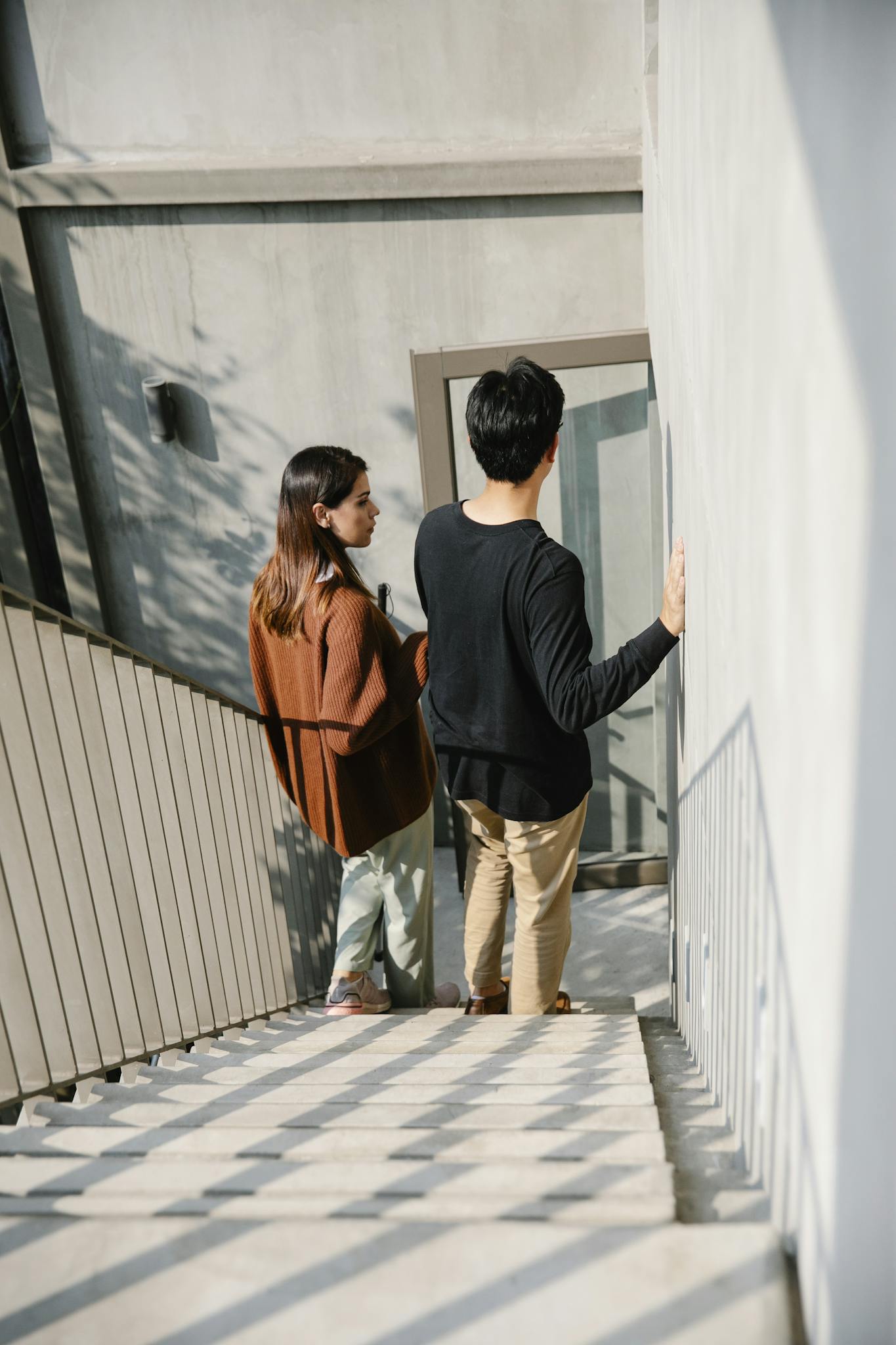 A man and woman descending an outdoor staircase together in daylight.