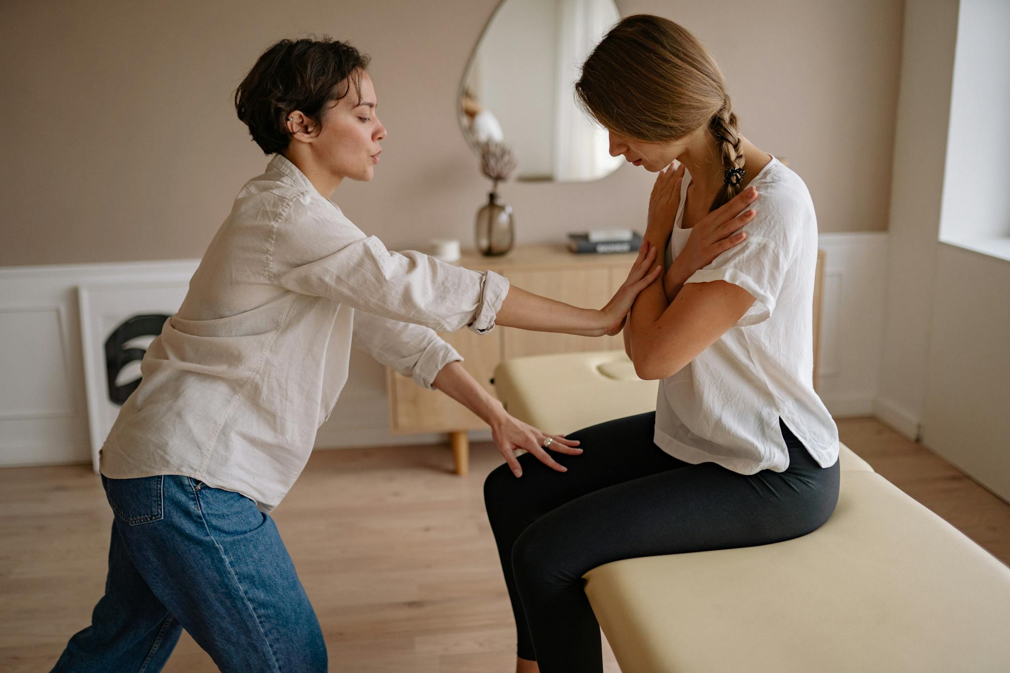 A therapist assisting a patient during a therapeutic session indoors, focusing on wellness and care.