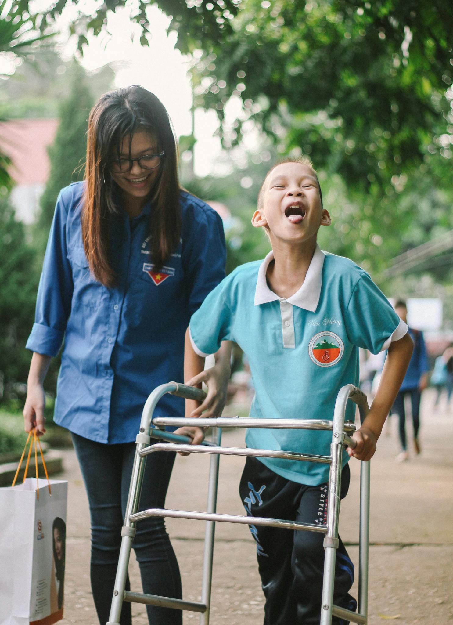 A joyful scene of a child using a walker with an assistant outdoors, embodying support and positivity.