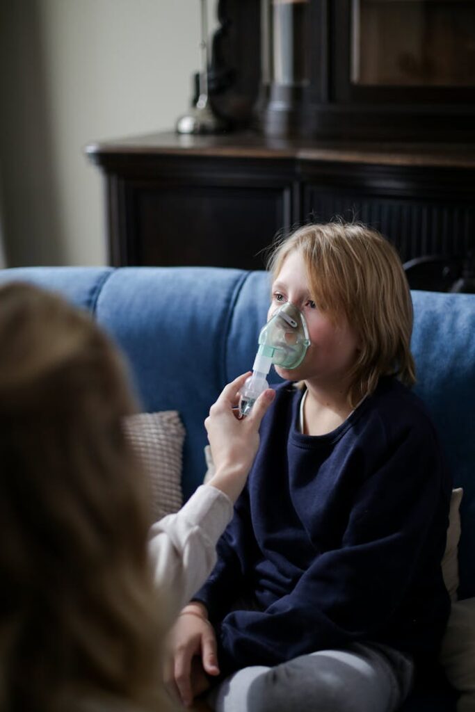 A young boy sits indoors receiving inhalation therapy, highlighting home healthcare.